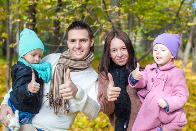 Familia de cuatro disfrutando las vacaciones de otoño y mostrando un pulgar hacia arriba