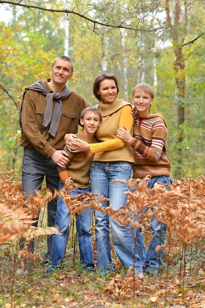 Familia de cuatro posando en el bosque de otoño