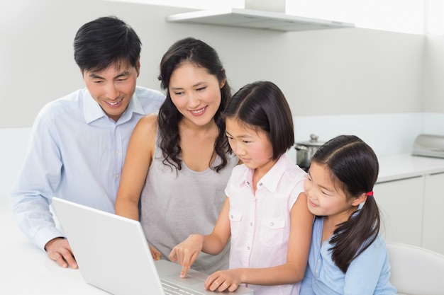 Familia de cuatro usando la computadora portátil en cocina