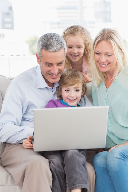 Familia de cuatro usando una computadora portátil