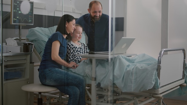 Foto família cumprimentando amigos remotos durante videochamada online usando o computador laptop em ho ...