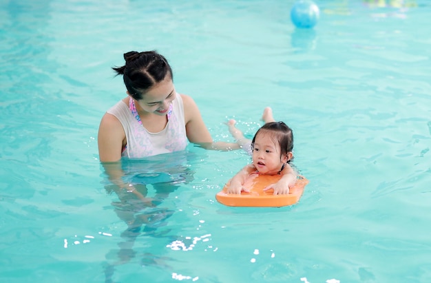 família da mãe ensinando criança na piscina