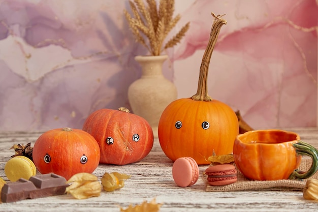 Família de abóbora de halloween feliz estética com olhos Abóboras sazonais engraçadas e fofas entre sobremesas xícaras de chá e cerejas de inverno Decorações de ação de Graças