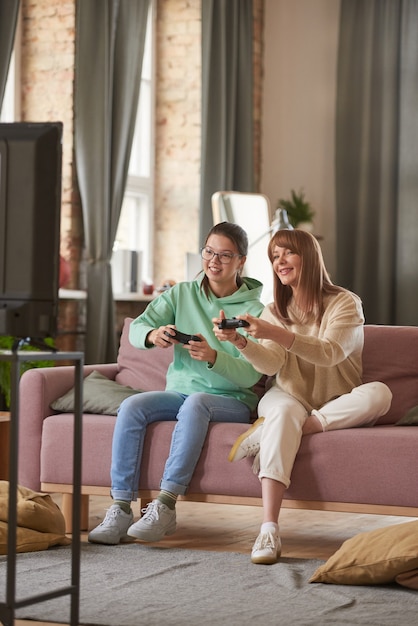 Família de duas pessoas sentadas no sofá e jogando videogame na TV na sala de estar