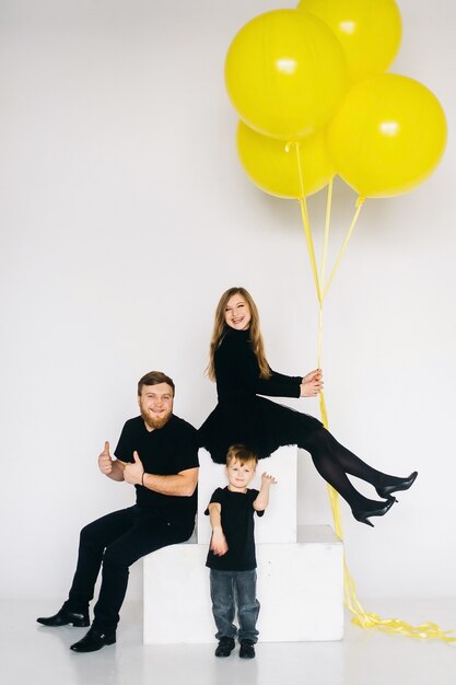 Foto família de estrela do rock com um grande balão amarelo. família elegante em roupas pretas