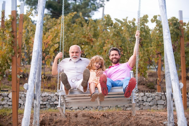 Família de geração de homens jogando juntos no balanço avô animado pai espantado e filho engraçado swin