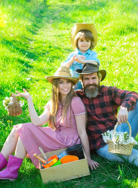 Foto família de jardineiro alegre sentado durante um piquenique no jardim. família jovem sorridente relaxante em dia de sol.