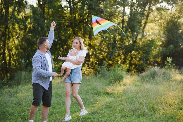 Família de jovem feliz, passando algum tempo juntos do lado de fora na natureza verde.