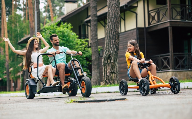 Família de jovem turista moderna e feliz de férias, andando de bicicleta e se divertindo juntos