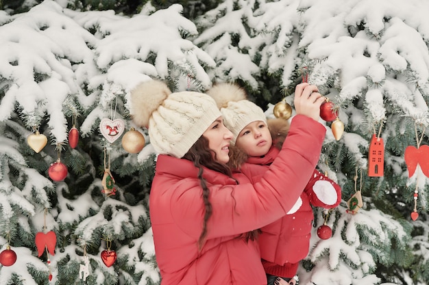 Família de natal em winter park. feliz família mãe e filha criança se divertindo, jogando no inverno a pé ao ar livre. diversão em família ao ar livre nas férias de natal. roupas de inverno para bebê e criança.