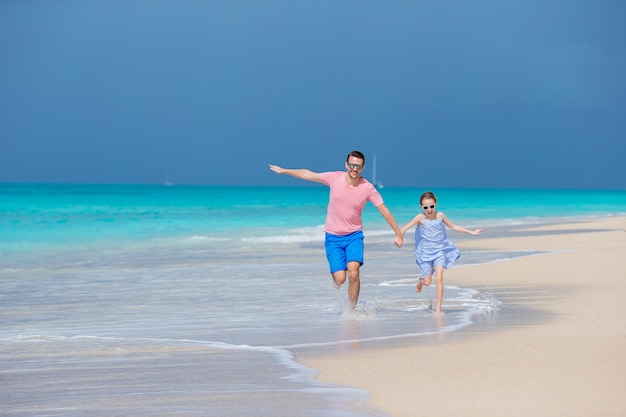 Família de pai e menina desportiva se divertindo na praia