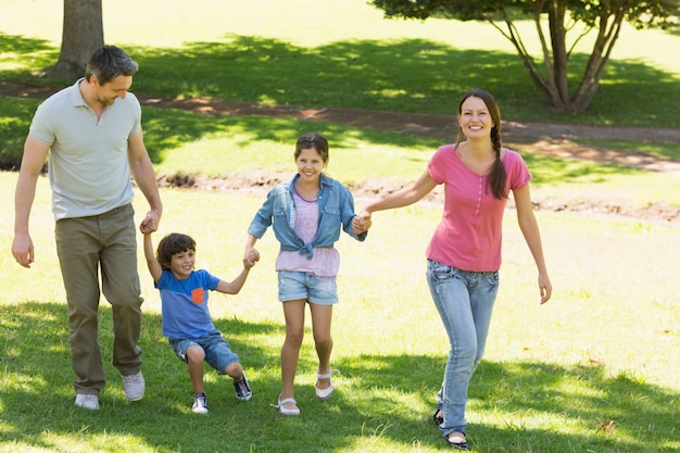 Família de quatro mãos dadas e caminhando no parque