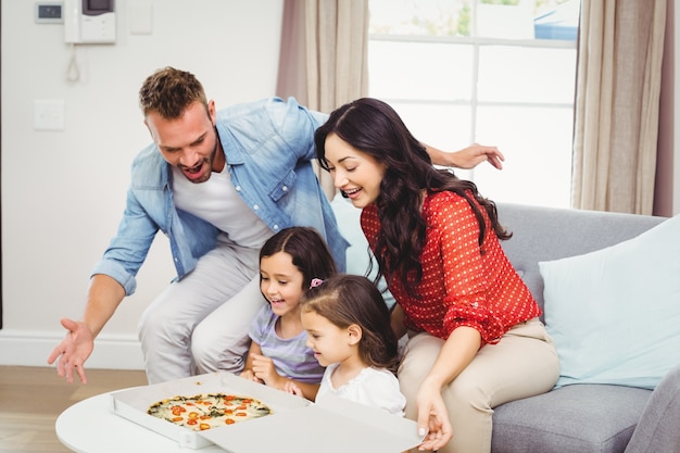 Família de quatro olhando para pizza na mesa