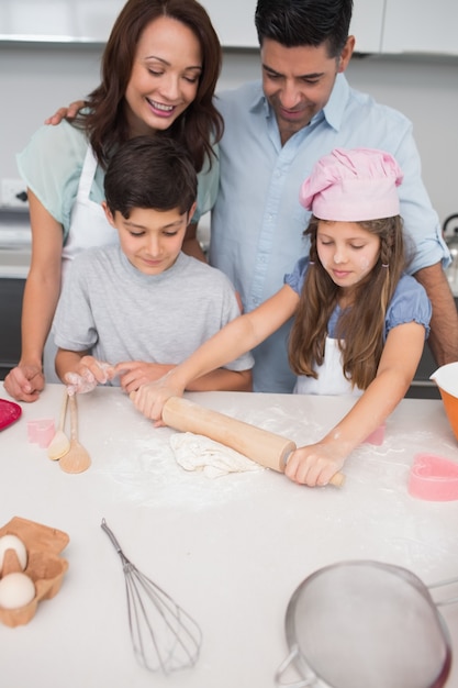 Família de quatro pessoas preparando biscoitos na cozinha