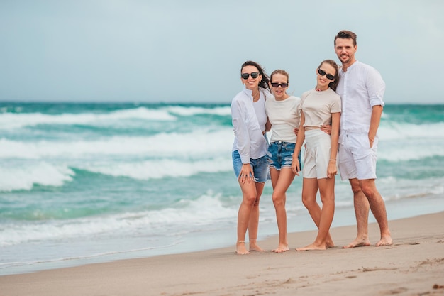 Família de quatro pessoas sorrindo e aproveitando o tempo juntos nas férias na praia