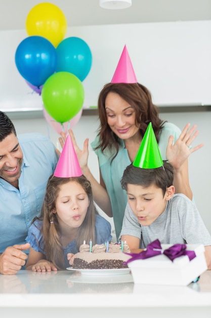 Família de quatro soprando bolo