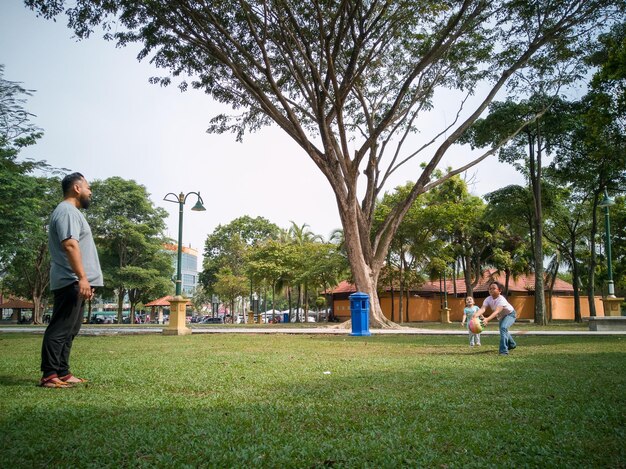 Foto família de três pessoas jogando bola no parque da malásia