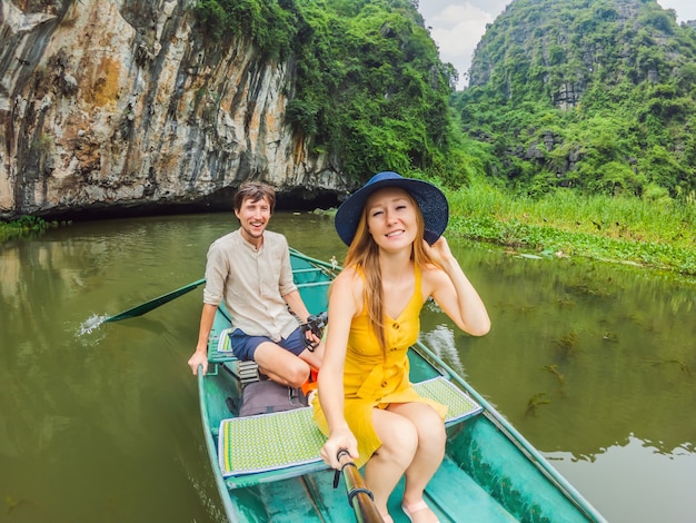 Família de turistas felizes em um barco no lago tam coc ninh binh vietnã é patrimônio mundial da unesco