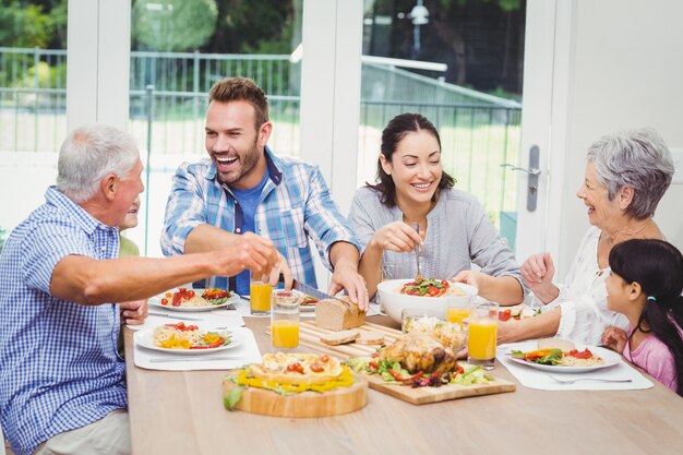 Família de várias gerações feliz com comida na mesa de jantar