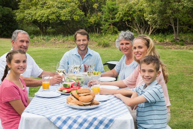 Família de várias gerações jantando fora na mesa de piquenique