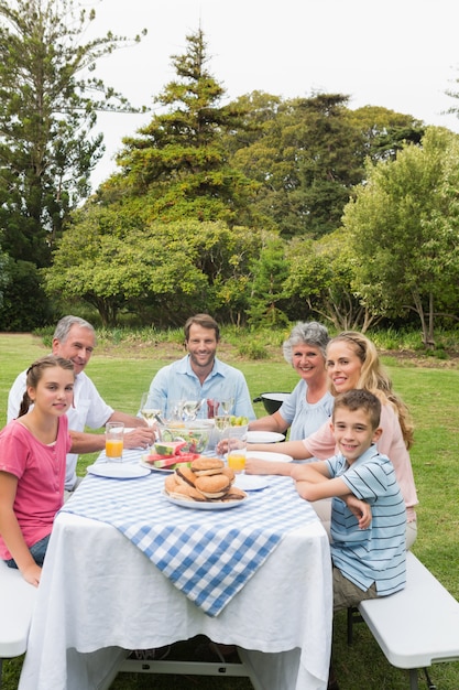 Família de várias gerações na mesa de piquenique, jantando fora