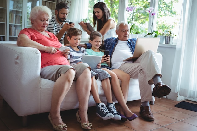 Família de várias gerações usando laptop, celular e tablet digital