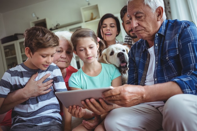 Família de várias gerações usando tablet digital na sala de estar