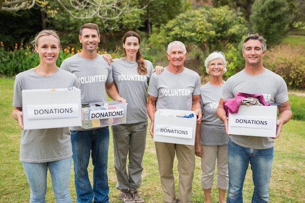 Família de voluntários feliz que dá caixas de doações