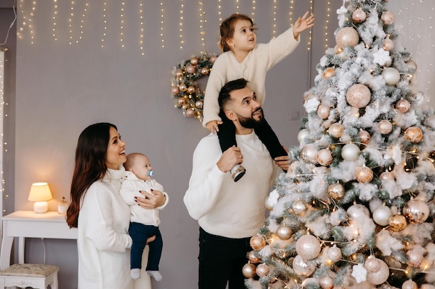 La familia decora el árbol de Navidad juntos en casa.