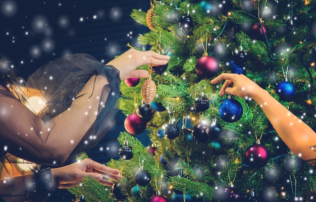 Una familia decora un árbol de Navidad por la noche. Enfoque selectivo. Fiesta.