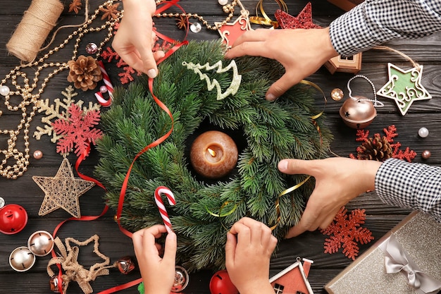 Familia decorar la corona de Navidad sobre fondo de madera