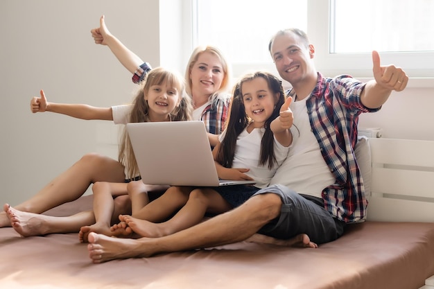 Família deitada na cama usando um laptop