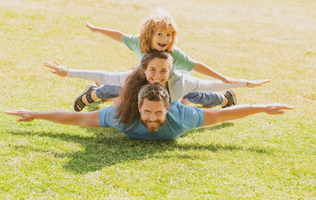 Família deitada na grama no parque Fly conceito garotinho está sentado enquanto imita o voo