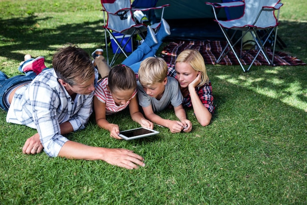 Família deitado na grama e usando tablet digital