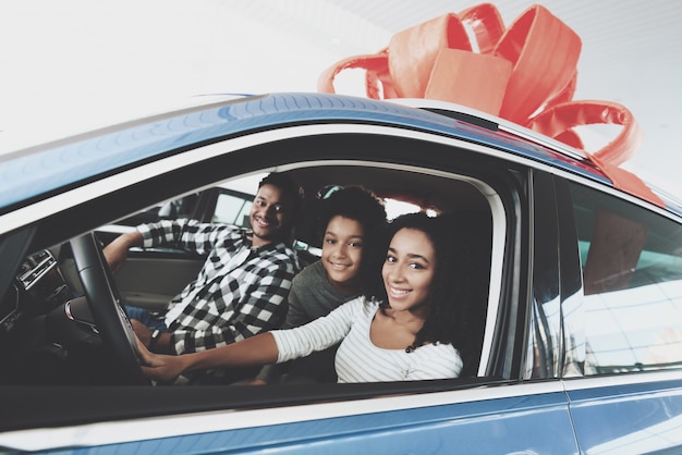 Familia dentro de coche nuevo con concepto de regalo de lazo rojo