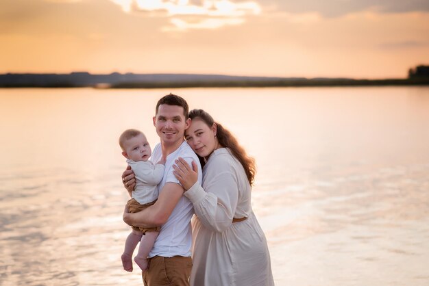 Familia descansando en un picnic en la playa cerca del mar, madre y padre sostienen a un niño, una familia feliz