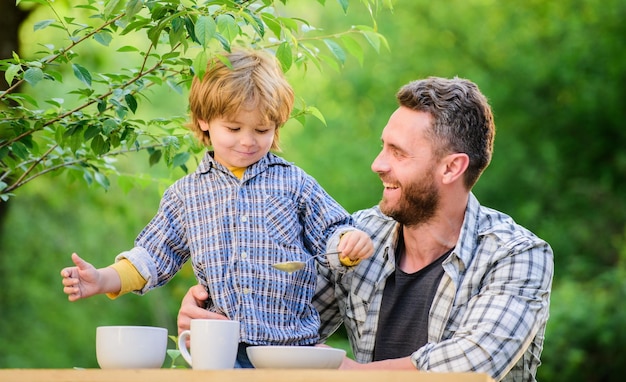 Família desfruta de refeição caseira Nutrição crianças e adultos Menino e pai comem Tudo é mais divertido com o pai Nutrição orgânica Conceito de nutrição saudável Hábitos de nutrição Criança segura colher