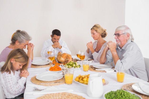 Familia diciendo gracia antes de comer un pavo