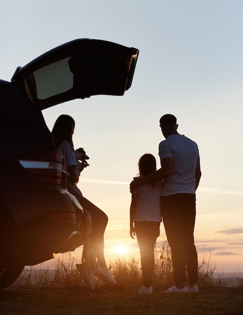 Foto la familia disfruta del atardecer desde la colina.