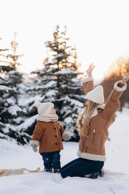 la familia se divierte en invierno en el parque con abetos