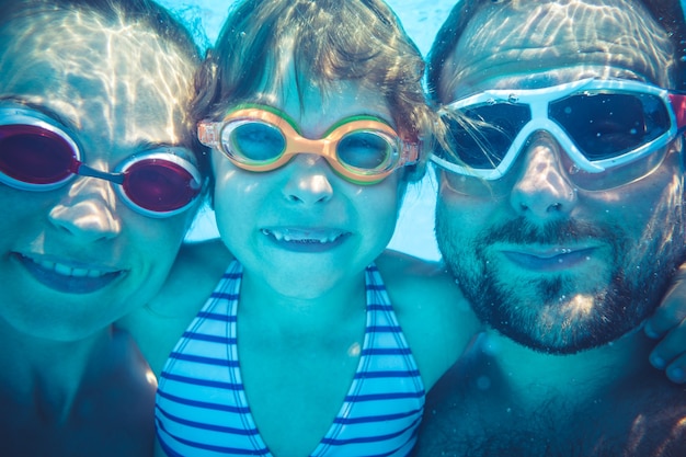 Familia divirtiéndose en la piscina bajo el agua divertido retrato vacaciones de verano