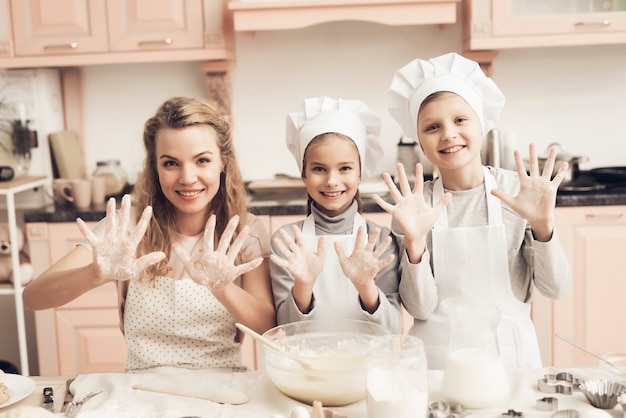 La familia doméstica de la hornada hace las manos de la pasta en harina.