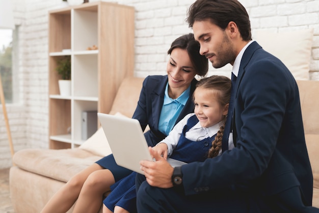 Família dos empresários que sentam-se no sofá em casa.