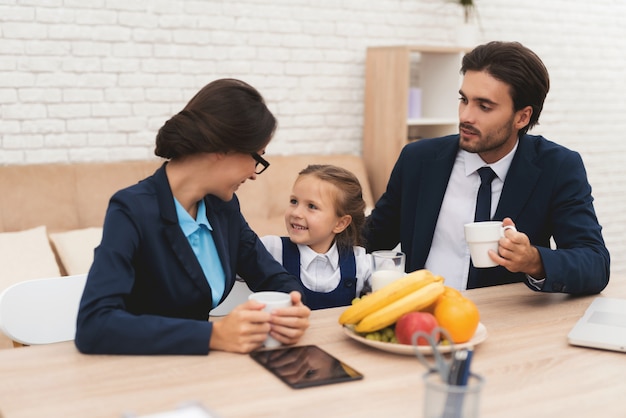 Família dos empresários que sentam-se no sofá em casa.