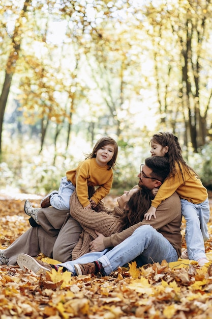 Familia con dos hijas sentadas en el parque en hojas de otoño