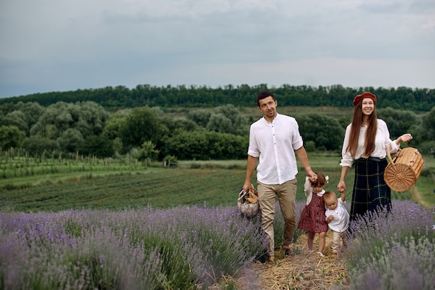 Una familia con dos hijos maravillosos camina sobre un campo de lavanda.