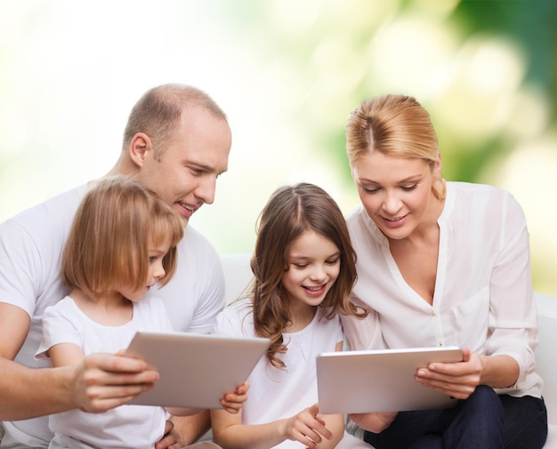família, ecologia, tecnologia e pessoas - sorrindo mãe, pai e filhas com computadores tablet pc sobre fundo verde