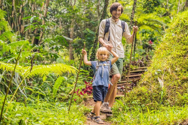 Família em caminhadas. pai e filho andando na floresta com bastões de trekking