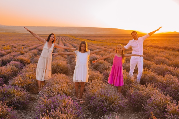 Família em campo de flores de lavanda ao pôr do sol com vestido branco e chapéu