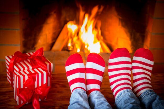 Família em meias de Natal perto da lareira. Mãe; pai e bebê se divertindo juntos. Pessoas relaxando em casa